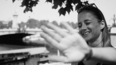 Paris, Fransa 'da yüzünü kameradan koruyan genç bir kadın. Arkasında bir köprü ve Seine nehri var.