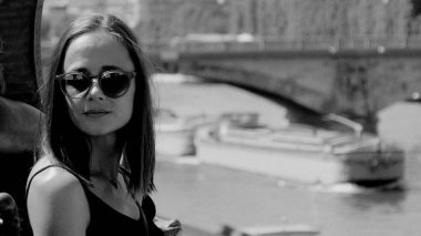 Paris 'teki şık genç kadının siyah beyaz portresi Seine nehri ve köprüsü arka planda.