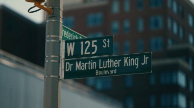 Batı 125. Cadde ve Dr. Martin Luther King Bulvarı için yeşil tabelalar. Arka planda New York Manhattan 'da bulanık bir bina var.
