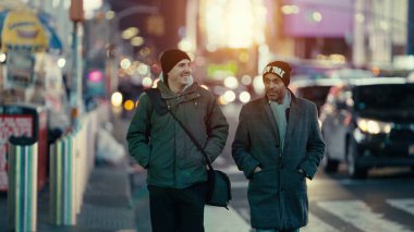 New York, Manhattan 'da birlikte yürüyen iki adam gün batımında konuşmanın tadını çıkarıyorlar.