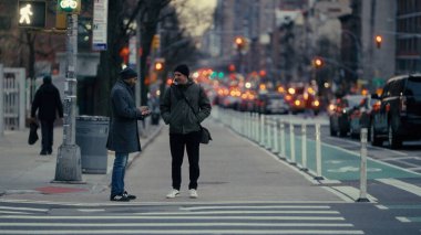 Trafiğin yoğun olduğu saatlerde Manhattan kaldırımında sohbet eden iki adam.