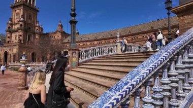 Plaza de Espana, Seville, İspanya 'daki süslü seramik parmaklıklarla merdivenlerden çıkan turistler, popüler bir turizm beldesi olan SEVILLE, SPAIN - 25 Mart 2025