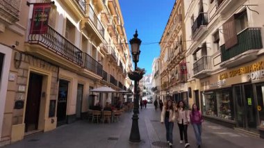 İspanya 'nın Cadiz kentinde dar bir caddeyi karakterize eden geleneksel mimari, balkonlar, bir sokak lambası ve açık mavi gökyüzü - CADIZ, SPAIN - 26 Mart 2025