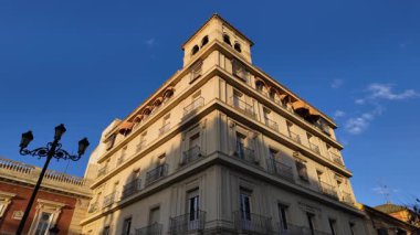 İspanya, Seville 'de balkon ve tenteleri olan bir binanın alçak açılı manzarası, altın saatin sıcacık ışığında yıkanmış.