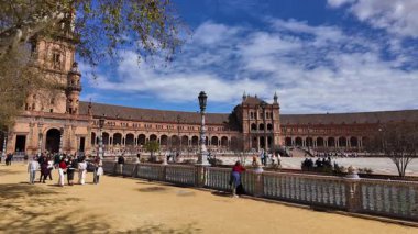 İspanya 'nın Sevilla kentindeki Plaza de Espana' da yürüyüş yapan ve güneşli bir günün tadını çıkaran turistler - SEVILLE, SPAIN - 25 Mart 2025