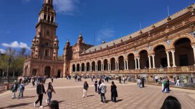 Güneşli bir günde İspanya 'nın Seville şehrinde bulunan Plaza de Espana Meydanı' nda yürüyen turistler - SEVILLE, SPAIN - 25 Mart 2025