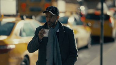 New York, Manhattan 'da fonda sarı taksilerle kahve içen ceketli bir işadamı.