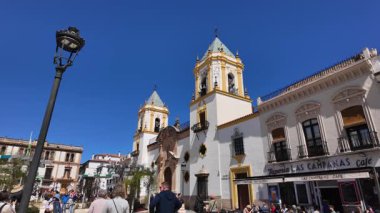 Plaza Duquesa de Parcent 'ta yürüyen turistler ve Santa Maria la Mayor kilisesi arka planda Ronda, İspanya - RONDA, İspanya - 28 Mart 2025