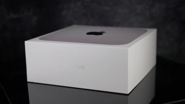 Unopened white box of an Apple Mac mini M1 chip computer reflecting on a dark glass surface - FRANKFURT, GERMANY - MAY 02, 2025