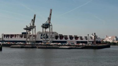 HAMBURG, GERMANY - 29 Nisan 2025 - Güneşli bir günde Hamburg, Almanya 'da büyük bir konteyner gemisi boşaltılıyor