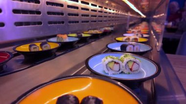 HAMBURG, GERMANY - 29 Nisan 2025 - Taze maki ve nigiri 'li renkli plakalar Koşan Suşi Bar kemeriyle taşınıyor