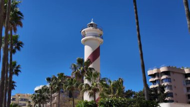 Güneşli bir günde beyaz ve kırmızı deniz feneri Marbella, İspanya 'da açık mavi gökyüzü ile yükseliyor.