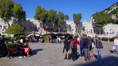 Güneşli bir günde Grand Casemates Meydanı, Cebelitarık 'ta yürüyen ve dinlenen turistler, arka planda restoranlar ve Cebelitarık Kayası - GIBRALTAR, İngiltere - 31 Mart 2025