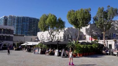 Genç kız Casemates Meydanı, Cebelitarık 'ta paten kayıyor, turistler ve yerel halkla güneşli bir günün tadını çıkarıyor - GIBRALTAR, İngiltere - 31 Mart 2025