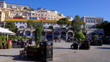 Güneşli bir günde Gibraltar 'daki Casemates Meydanı' ndaki restoran ve banklarda oturan insanlar - GIBRALTAR, İngiltere - 31 Mart 2025