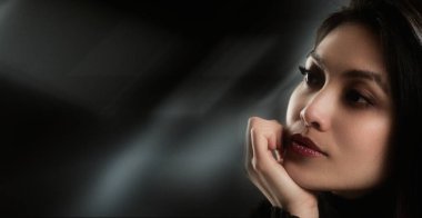 Derin düşüncelere dalmış bir kadın, çenesini elinin üzerinde dinlendiriyor.