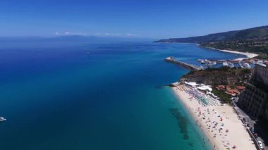 Tropez sahil şeridinin çarpıcı hava manzarası, kristal berrak turkuaz suları ve yaz tatili boyunca plajda dinlenen turistler.