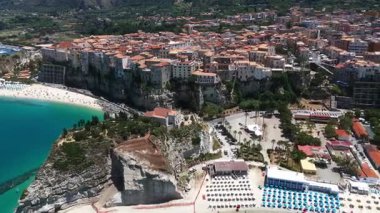 Tropea, İtalya 'nın hava manzarası, renkli plaj şemsiyeleri, uçuruma tünemiş evler ve güzel sahil şeridi.