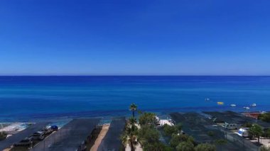 Tropez sahil şeridinin çarpıcı hava manzarası, kristal berrak turkuaz sular, sakin bir sahil otoparkı ve yemyeşil bitki örtüsü.