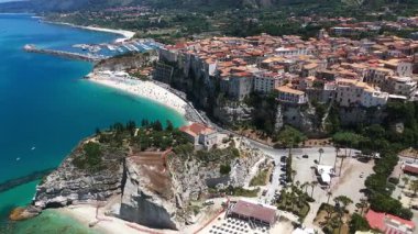 Tropea, İtalya 'nın hava manzarası, renkli plaj şemsiyeleri, uçuruma tünemiş evler ve güzel sahil şeridi.