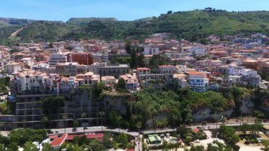 Tropea, İtalya 'nın hava manzarası, renkli plaj şemsiyeleri, uçuruma tünemiş evler ve güzel sahil şeridi.