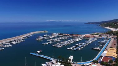 Ufukta görünen Tropea turistik limanının birçok yat ve motorlu teknesi, açık mavi Tyrhenian Denizi ve Aeolian Adaları görünüyor.