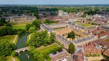 Güneşli bir yaz gününde, Cambridge Üniversitesi 'nin tarihi binalarından akan Cam nehrinde kayan turistler.
