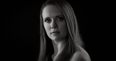 Stüdyoda uzun saçlı, ciddi bir beyaz kadının siyah beyaz portresi.