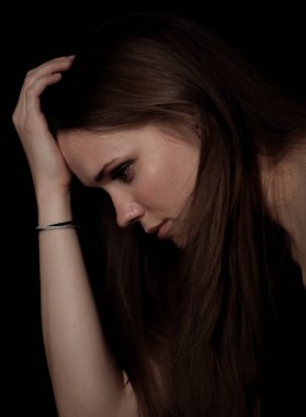 Baş ağrısı ya da depresyondan muzdarip üzgün genç bir kadın elini siyah arka planda tutuyor.