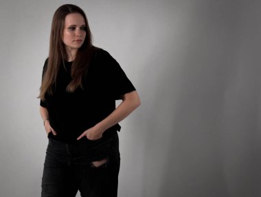 Gündelik giysiler giymiş, derin düşüncelere dalmış genç bir kadının stüdyo portresi.