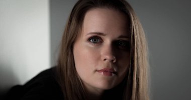 Uzun kahverengi saçlı ve ciddi bir ifadeyle güzel bir genç kadının stüdyo portresi.