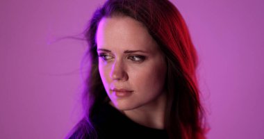 Uzun kahverengi saçlı genç bir kadının stüdyo portresi, renkli neon ışıklarla aydınlatılmış, canlı ve modern bir görünüm yaratıyor.