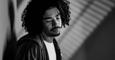 Siyah beyaz, kıvırcık saçlı genç bir Afrikalı Amerikalı 'nın portresi. Üzüntü ve iç gözlem ifade ediyor.