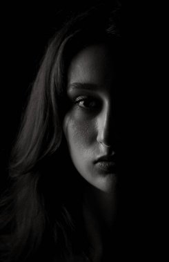 Gölgelerden yükselen genç bir kadının dramatik siyah beyaz portresi.