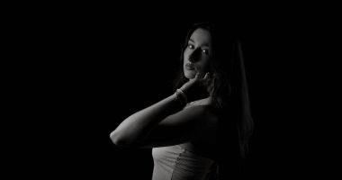 Uzun saçlı, elleriyle yüzüne dokunan beyaz bir kadının stüdyo portresi.