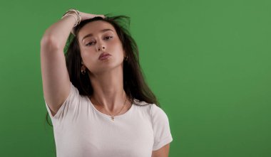 Renkli anahtar arka planında poz veren manken, saçına dokunuyor.