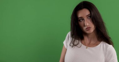 Yeşil ekran arka planına bakan genç bir kadının stüdyo görüntüsü.