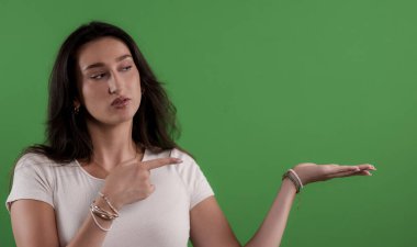 Açık elini gösteren genç bir kadın yeşil krom anahtar arka planında bir şey gösteriyor.