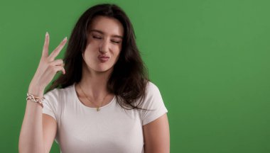 Krom anahtar arka planda barış işareti gösteren komik suratlar yapan genç bir kadın.