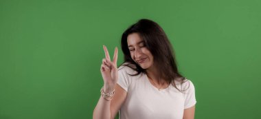 Neşeli genç bir kadın iki parmağı krom anahtarda zafer jesti yapıyor.