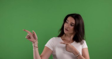 Yeşil ekran arka planında işaret parmağı olan genç bir kadın.