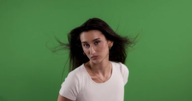 Stüdyo portresi, kendine güvenen esmer, yeşil perde arkasında saç kesimi olan genç bir kadın.