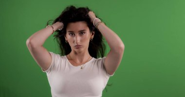 Uzun saçlarını tutan, elleri krom anahtarlı genç bir kadın.