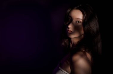 Yüzüne ilginç gölgeler yansıyan genç bir kadının stüdyo portresi dramatik ve gizemli bir atmosfer yaratıyor.