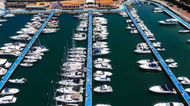 Birçok beyaz yat ve motorlu tekne güneşli bir yaz gününde İtalya 'nın Calabria kentindeki Tropea marinasının mavi rıhtımına demirlemiştir.