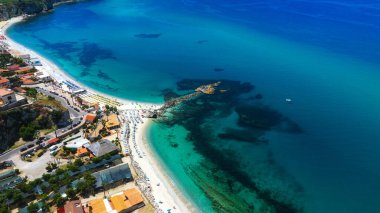 Tropea, Calabria 'nın hava manzarası, kristal berrak turkuaz sular, plaj şemsiyeleri ve resim gibi bir kıyı şeridi.