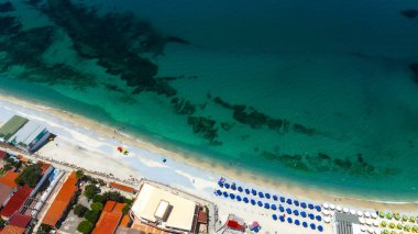 Tropea sahilinin nefes kesici hava manzarası, kristal berrak turkuvaz suları, sahil şemsiyeleri ve İtalya 'nın Calabria kentindeki büyüleyici sahil kasabası