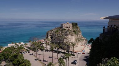 Santa Maria dell Isola 'nın panoramik manzarası, kayalık bir adaya tünemiş tarihi bir kilise, ön planda Tropea plajı ve arka planda Tyrhenian Denizi
