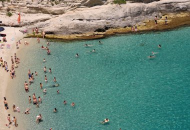 TROPEA, İTALYA - 02 Haziran 2025 - Tropea sahilinin berrak turkuaz suyunda yüzen ve güneşlenen turistler, Güney İtalya