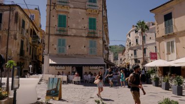 TROPEA, İTALYA - HAZİRAN 02, 2025 - Tropea, İtalya 'nın ana caddesinde güneşli bir yaz gününde restoranlar ve dükkanlar arasında yürüyen turistler